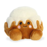 Cinnamon Roll plush from Palm Pals, golden brown with frosting drizzle, designed to resemble a cinnamon roll.