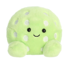 Plush toy of a light green pickle in the Palm Pals collection with white spots and a cheerful face.