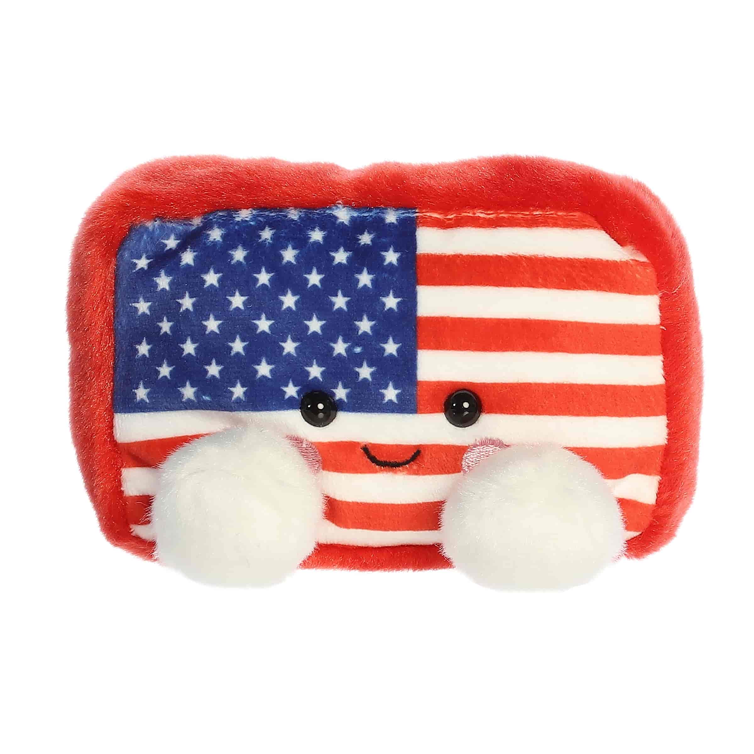 A small red, white, and blue flag plush with embroidered cheeks from Palm Pals by Aurora.