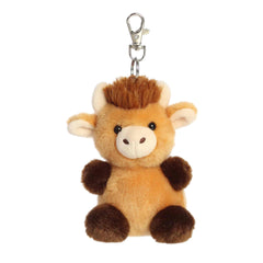 A small brown Highland cow plush clip-on with fluffy fur and a cream muzzle from Palm Pals by Aurora.