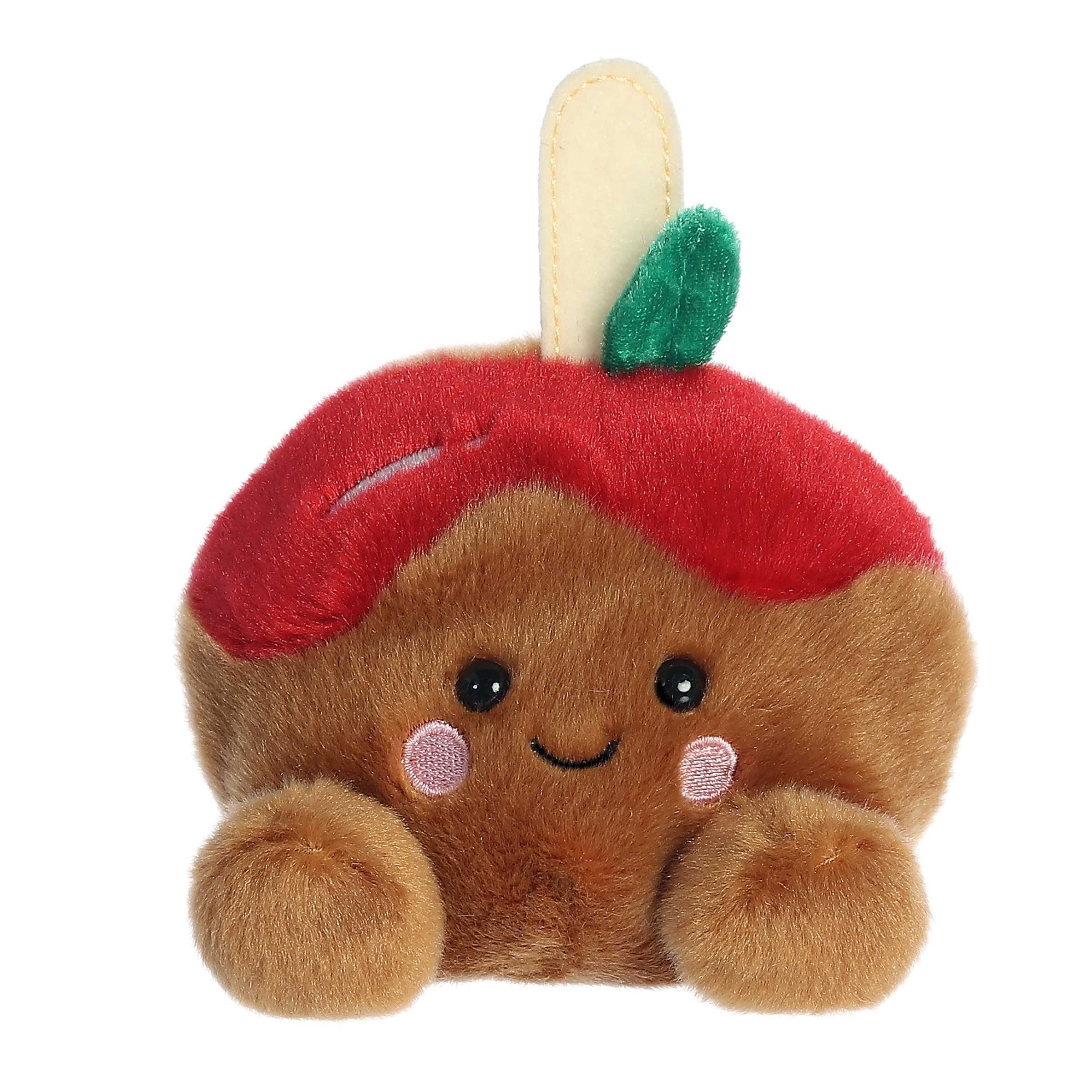 A delightful red apple plush on a stick that has been dipped in a sticky brown caramel sauce and a blushing smile
